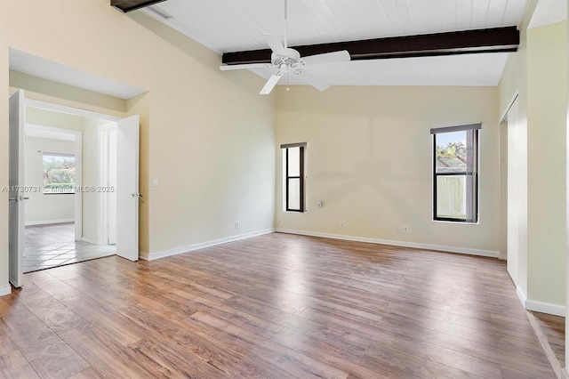 unfurnished room featuring vaulted ceiling with beams, ceiling fan, plenty of natural light, and light wood-type flooring