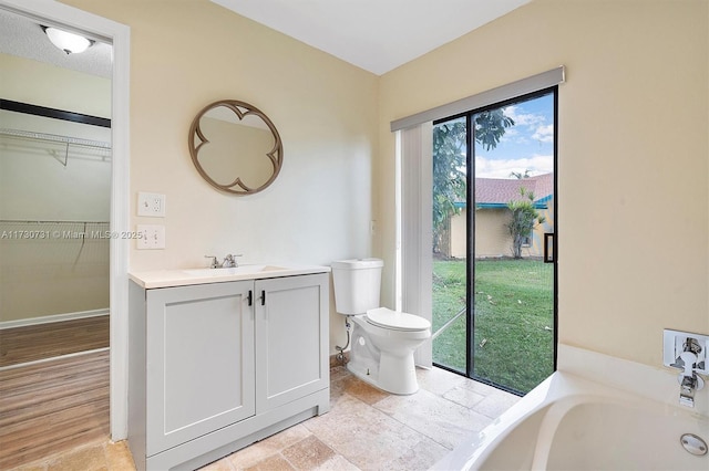 bathroom featuring vanity, toilet, and a tub