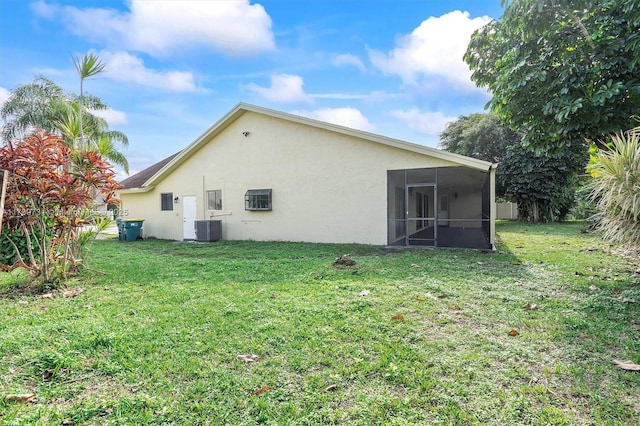 rear view of house with cooling unit, a yard, and a sunroom