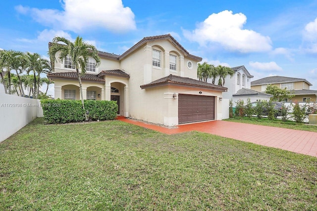 mediterranean / spanish home with an attached garage, fence, decorative driveway, stucco siding, and a front yard