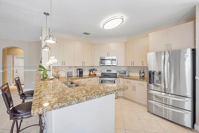 kitchen with stainless steel appliances, a peninsula, a sink, visible vents, and a kitchen breakfast bar