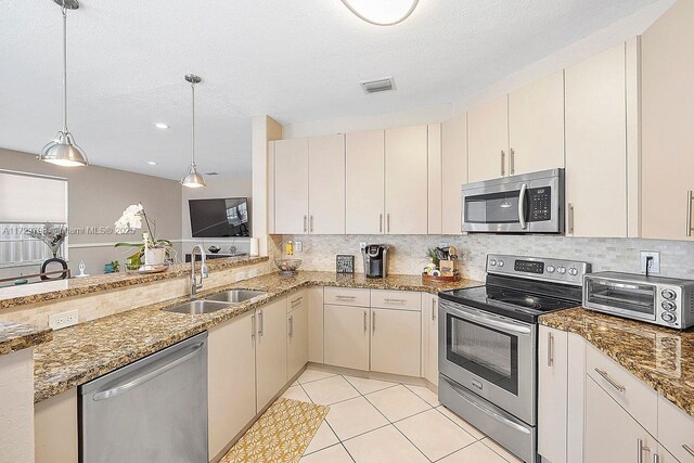 kitchen featuring stainless steel appliances, sink, a textured ceiling, and decorative light fixtures