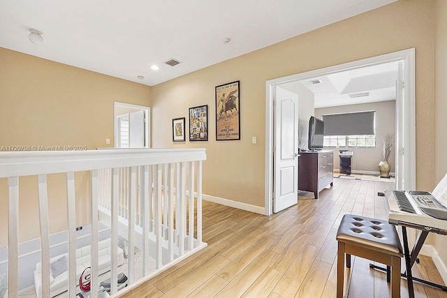 hall with light wood-style floors, baseboards, and visible vents