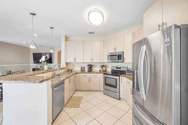 kitchen with appliances with stainless steel finishes, sink, hanging light fixtures, light tile patterned floors, and kitchen peninsula