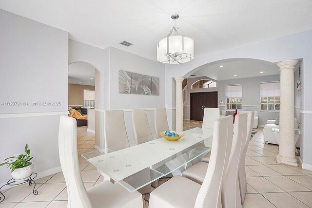 dining area featuring light tile patterned floors, a notable chandelier, and ornate columns