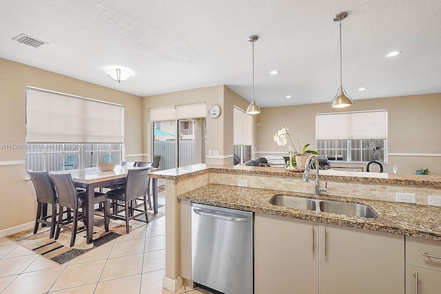 kitchen with stone countertops, visible vents, dishwasher, decorative light fixtures, and a sink