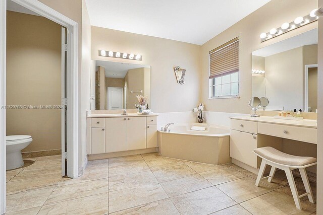 bathroom with a washtub, vanity, tile patterned floors, and toilet