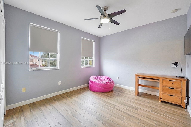 interior space with light wood-style floors, baseboards, and a ceiling fan