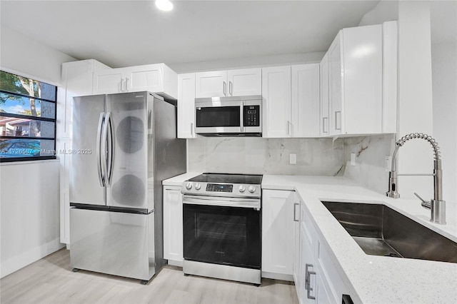 kitchen with sink, white cabinetry, stainless steel appliances, and decorative backsplash