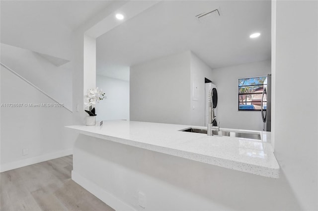 kitchen featuring light hardwood / wood-style floors, sink, stainless steel fridge, and light stone counters