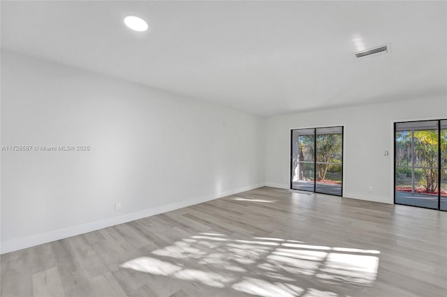 empty room with light hardwood / wood-style floors and plenty of natural light