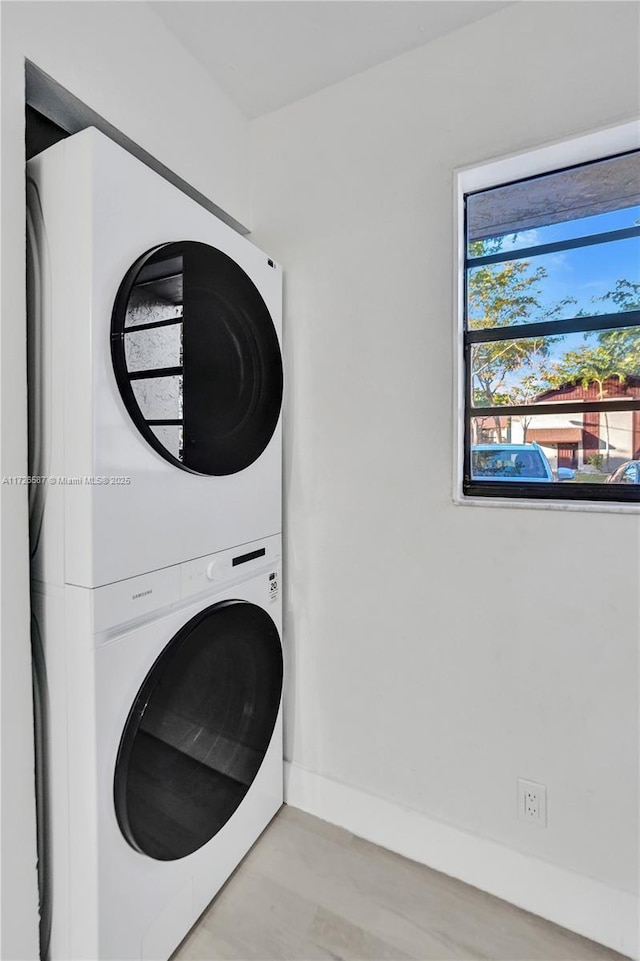 laundry room with light wood-type flooring and stacked washing maching and dryer