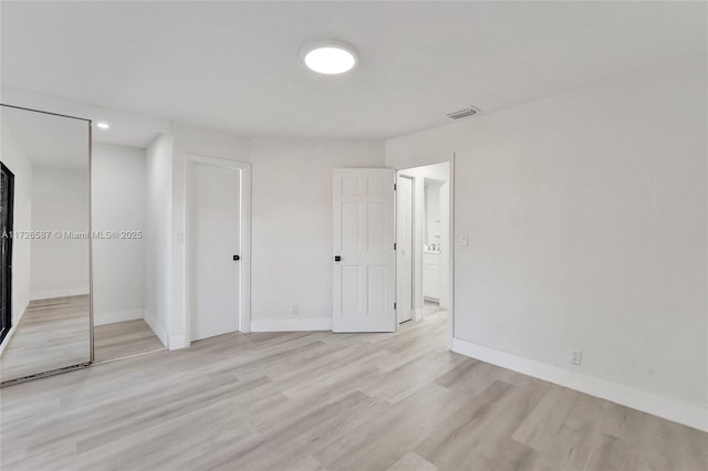 unfurnished bedroom with light wood-type flooring and a closet