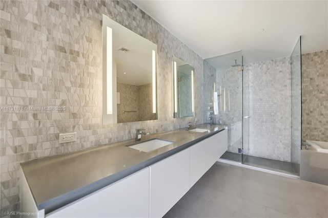 bathroom with a shower with door, vanity, tile patterned flooring, and tile walls