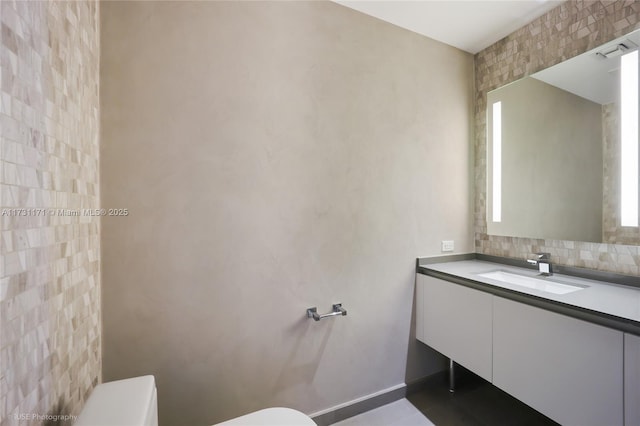 bathroom featuring vanity, toilet, and decorative backsplash