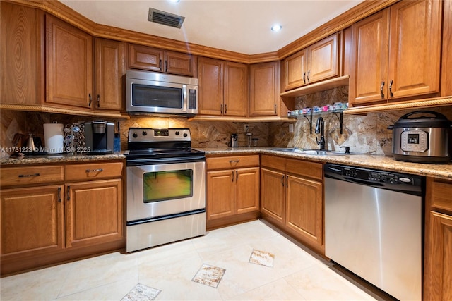 kitchen featuring sink, light tile patterned floors, stone counters, stainless steel appliances, and decorative backsplash