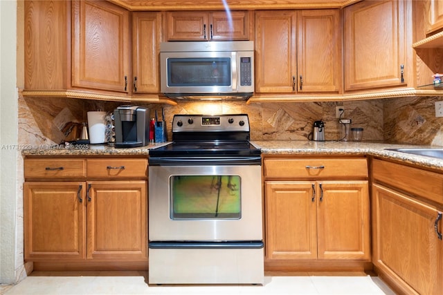 kitchen with tasteful backsplash, stainless steel appliances, light stone counters, and light tile patterned floors