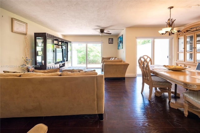 living room featuring dark hardwood / wood-style floors, ceiling fan with notable chandelier, and a textured ceiling