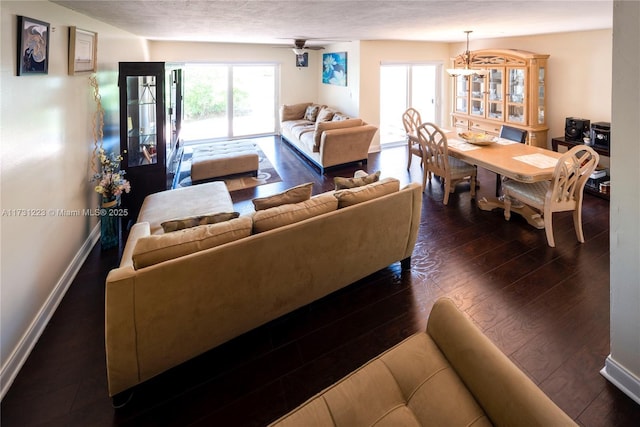 living room with dark hardwood / wood-style floors and ceiling fan with notable chandelier