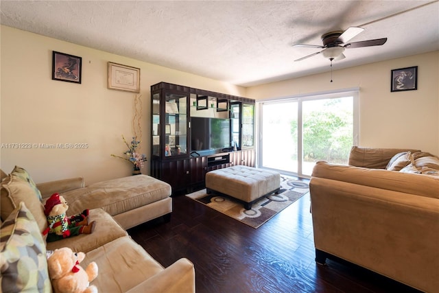 living room featuring ceiling fan, dark hardwood / wood-style flooring, and a textured ceiling