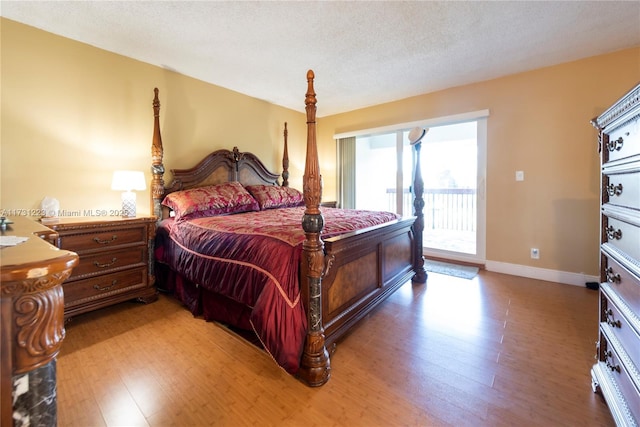 bedroom featuring hardwood / wood-style flooring, access to outside, and a textured ceiling