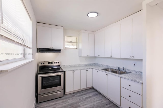 kitchen with stainless steel electric range oven, sink, light hardwood / wood-style flooring, and white cabinets