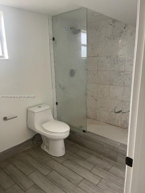 bathroom with tiled shower and toilet