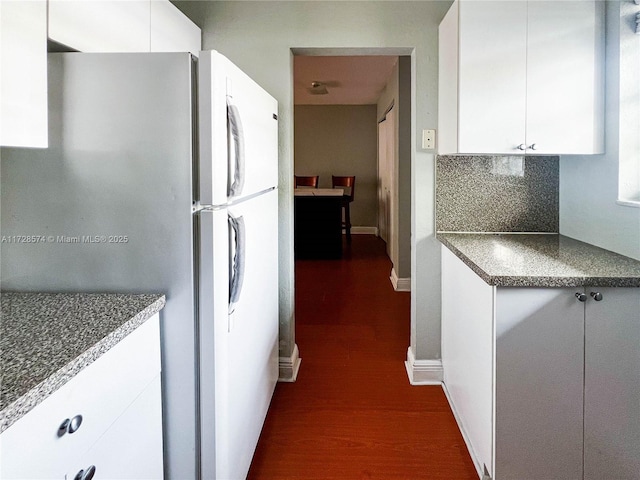 kitchen with white refrigerator, white cabinetry, dark wood-type flooring, and tasteful backsplash