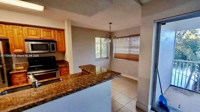 kitchen featuring sink, decorative light fixtures, light tile patterned floors, appliances with stainless steel finishes, and dark stone counters