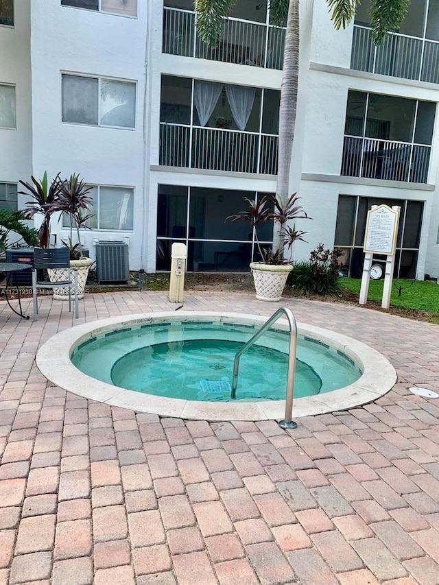 view of swimming pool with cooling unit and an in ground hot tub