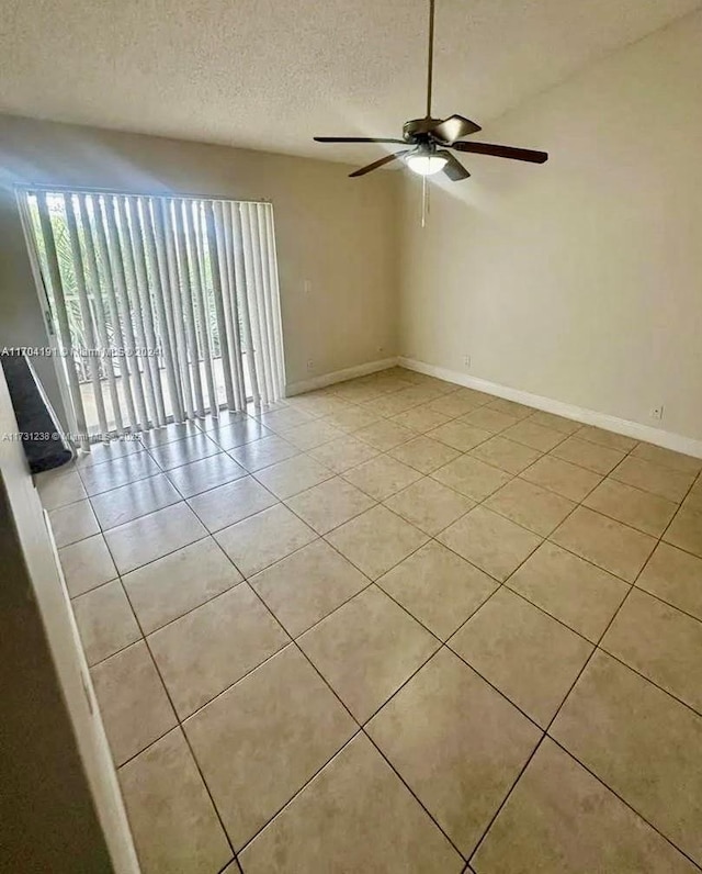 tiled empty room featuring ceiling fan and a textured ceiling