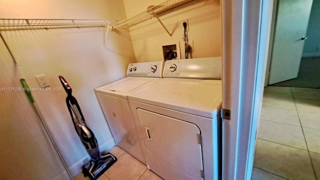 clothes washing area featuring washer and clothes dryer and light tile patterned floors