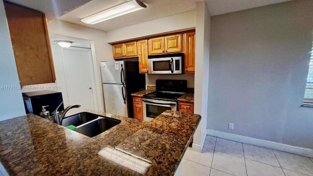 kitchen featuring sink, light tile patterned floors, stainless steel appliances, and kitchen peninsula