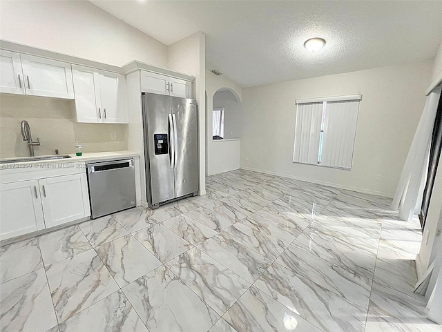 kitchen with sink, vaulted ceiling, stainless steel fridge with ice dispenser, dishwashing machine, and white cabinets