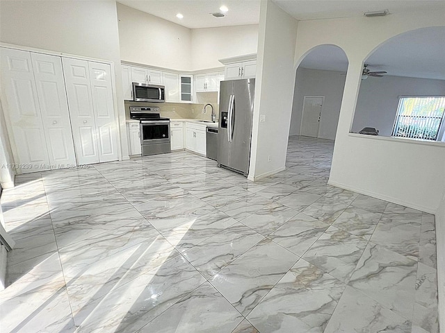 kitchen featuring high vaulted ceiling, white cabinetry, sink, ceiling fan, and stainless steel appliances