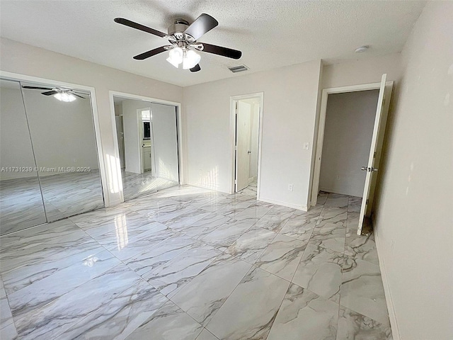 unfurnished bedroom featuring multiple closets, ceiling fan, and a textured ceiling