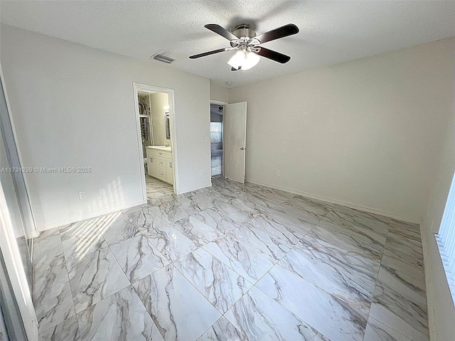 unfurnished bedroom with ceiling fan, ensuite bath, and a textured ceiling