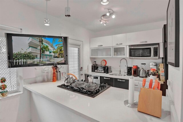 kitchen with white cabinetry, sink, black gas stovetop, and decorative light fixtures