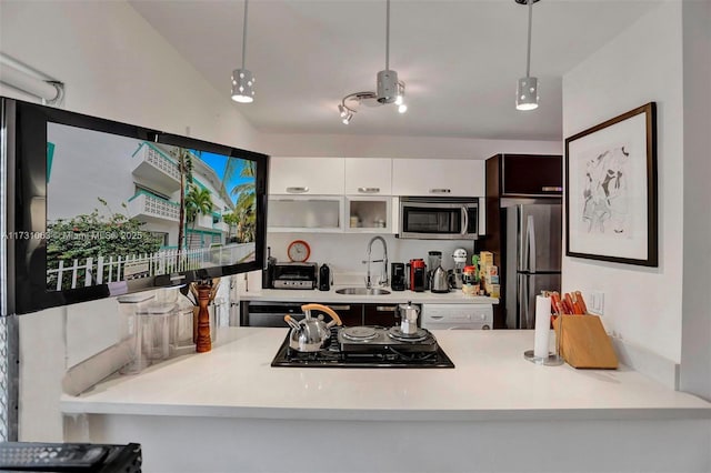 kitchen featuring hanging light fixtures, stainless steel appliances, sink, and white cabinets