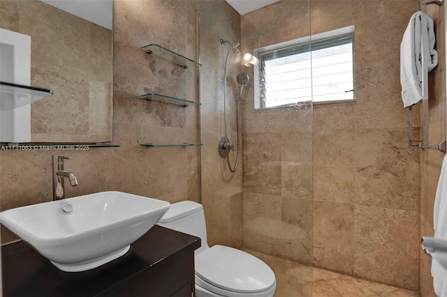 bathroom featuring a tile shower, vanity, and toilet