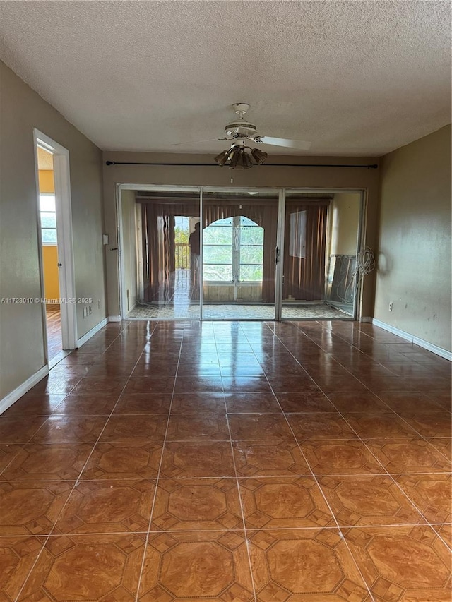 spare room with ceiling fan, tile patterned flooring, and a textured ceiling