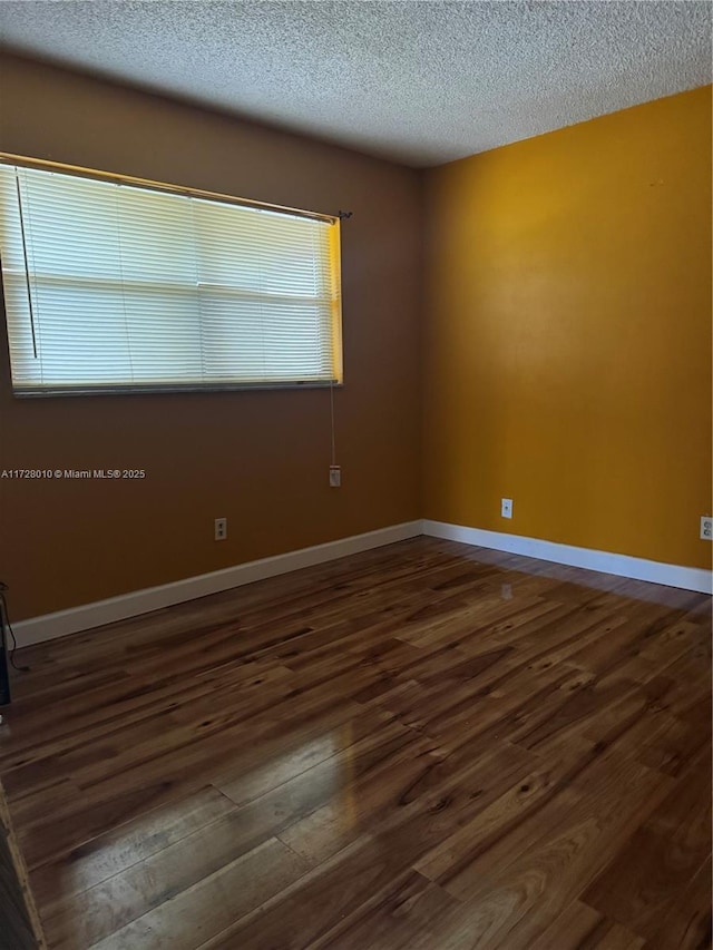 unfurnished room featuring dark wood-type flooring and a textured ceiling