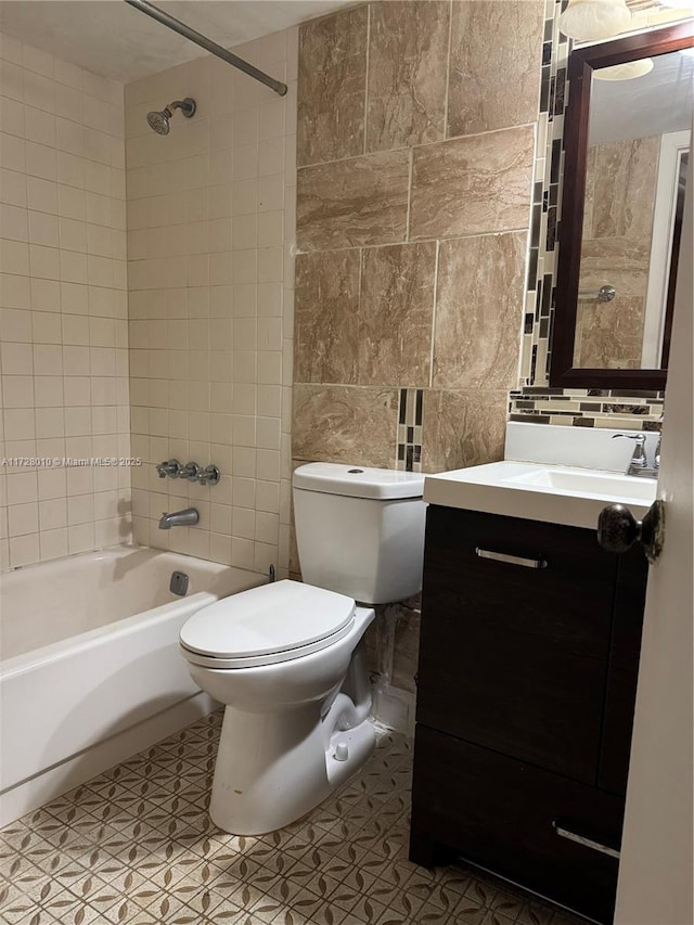 full bathroom featuring tile walls, vanity, tiled shower / bath, tile patterned floors, and toilet