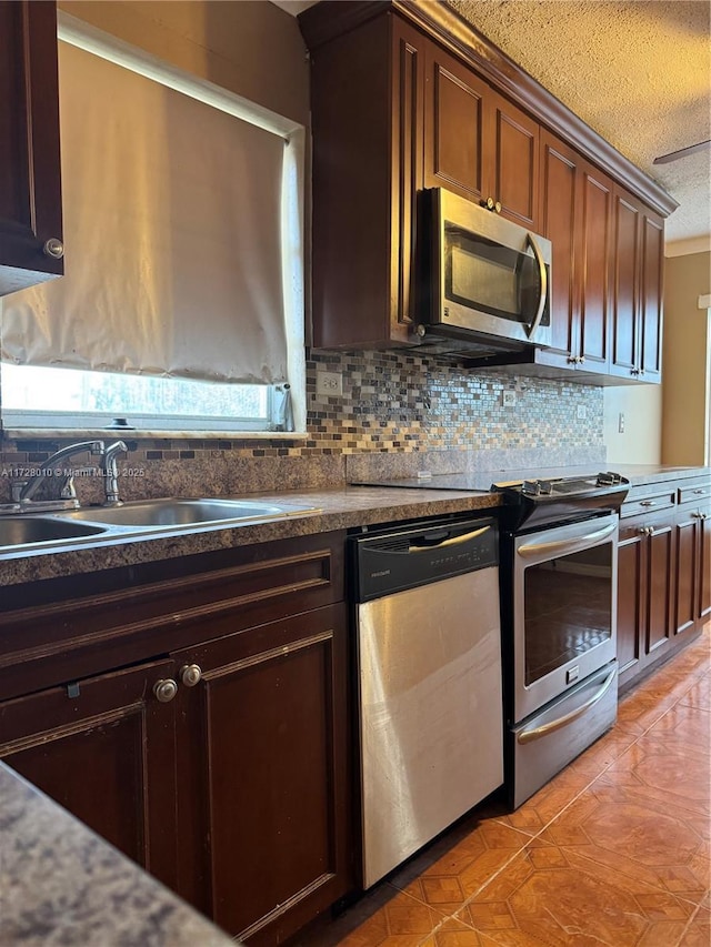 kitchen with tasteful backsplash, sink, light tile patterned floors, stainless steel appliances, and a textured ceiling