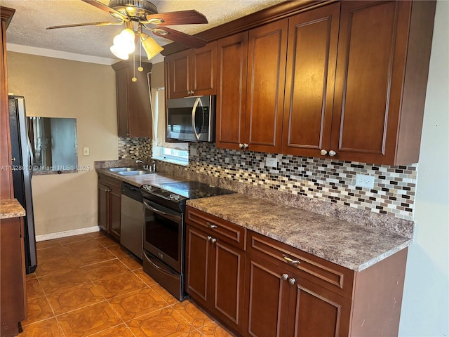 kitchen with sink, a textured ceiling, dark tile patterned flooring, stainless steel appliances, and decorative backsplash