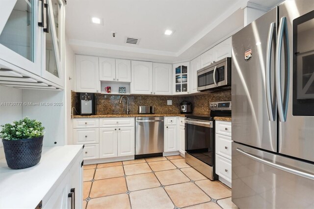 kitchen with sink, appliances with stainless steel finishes, dark stone countertops, white cabinets, and decorative backsplash