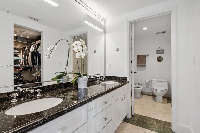 bathroom with tile patterned flooring, a bidet, vanity, and toilet