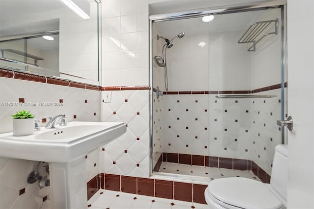 bathroom featuring tasteful backsplash, sink, tile walls, tiled shower, and toilet