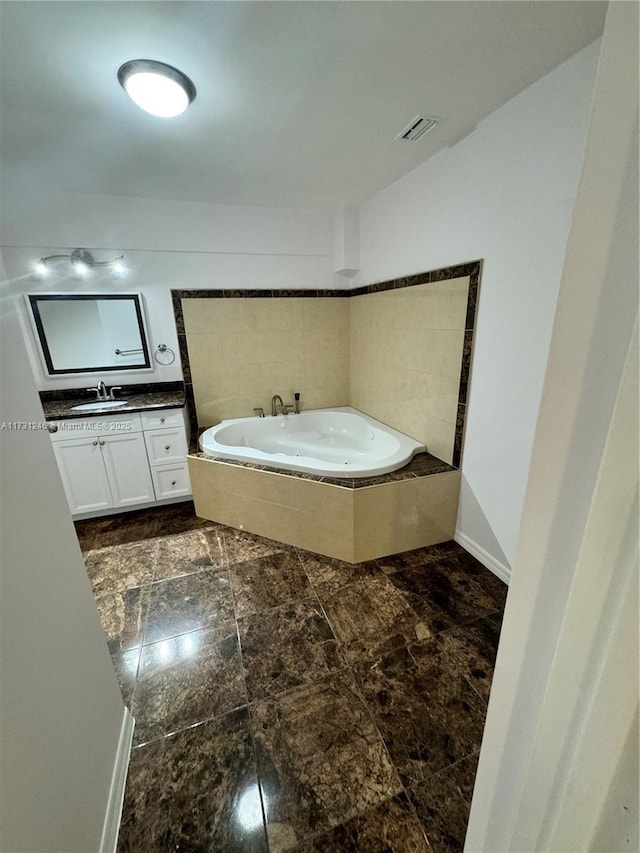 bathroom featuring vanity and tiled tub