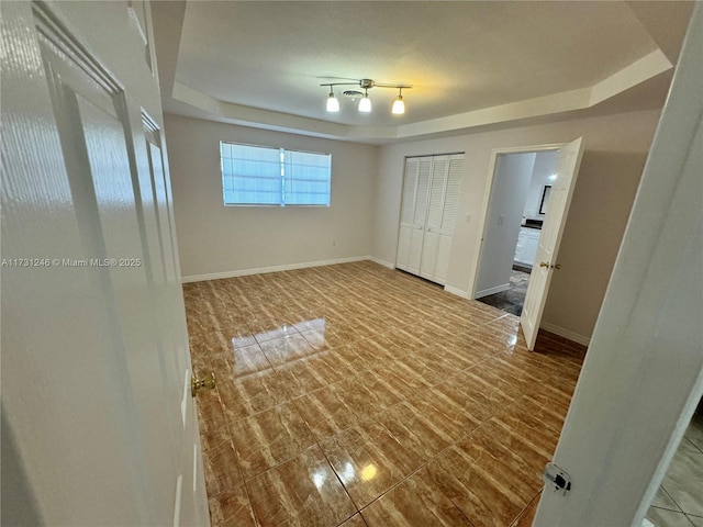 unfurnished bedroom featuring a tray ceiling and a closet